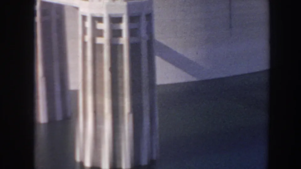 Handheld 8mm frame of Hoover Dam with the edge of an intake tower, dark water below, and a shadowed concrete surface.