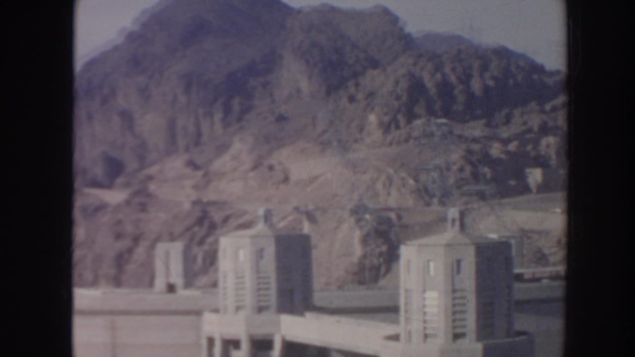 Hoover Dam towers and arid mountain ridges appear in a soft 1962 home-movie frame.