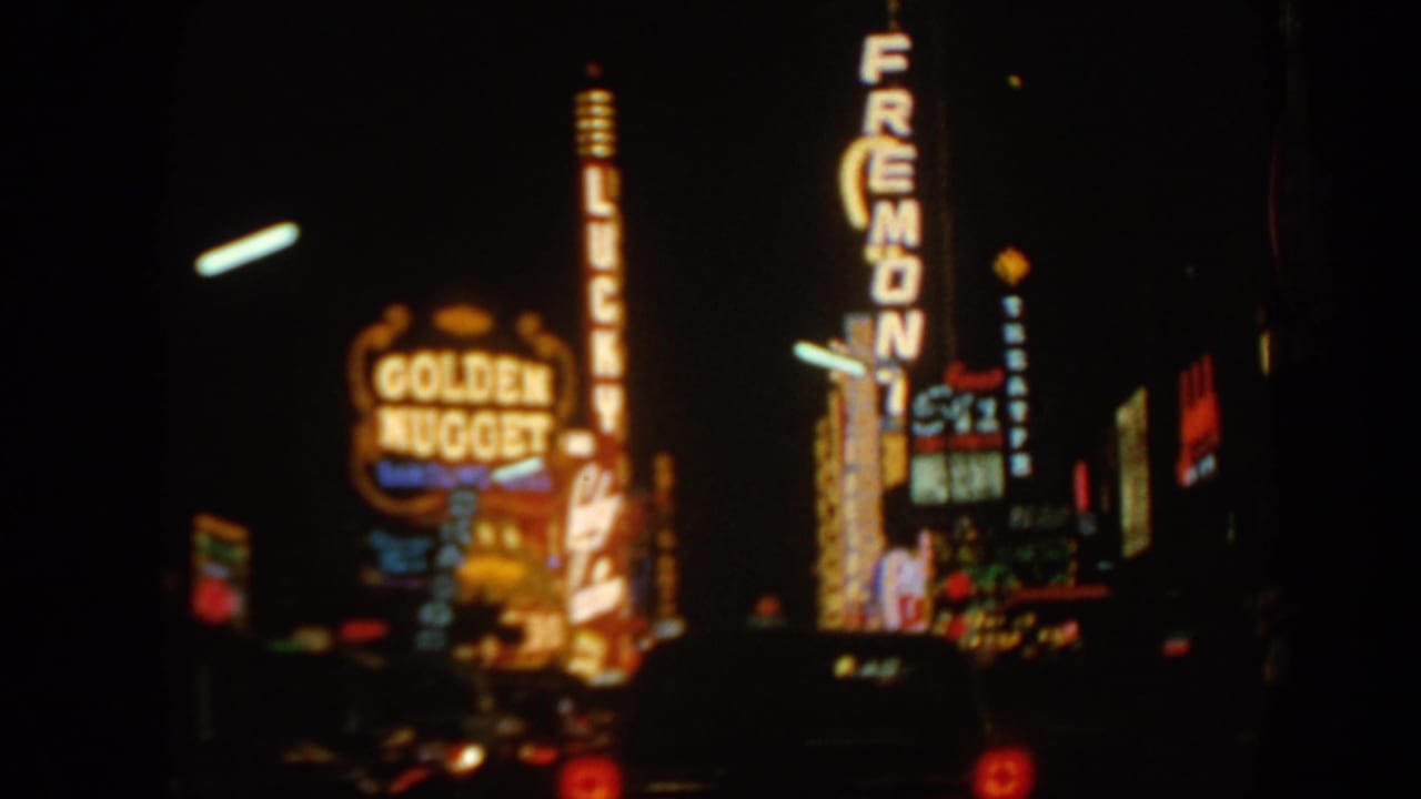 1960s 8mm view of Las Vegas neon at night, including Golden Nugget and Fremont signs seen from a dark street.