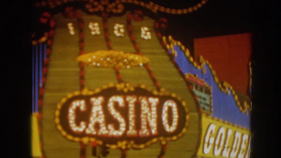 Close 1962 Las Vegas night frame showing a large illuminated casino sign with rows of bulbs and partial Golden Nugget signage.
