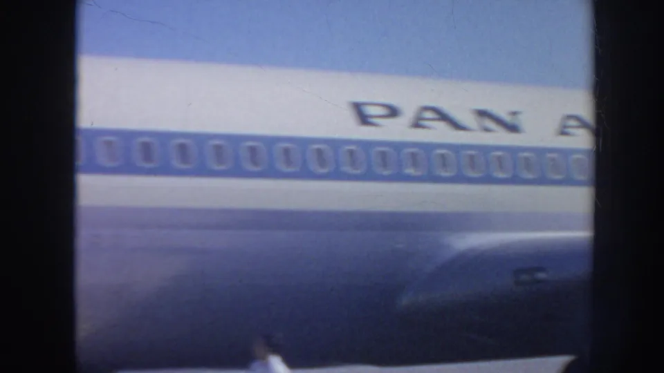 Close 1962 home-movie view of the Pan Am aircraft fuselage, showing the blue window band and partial airline lettering.