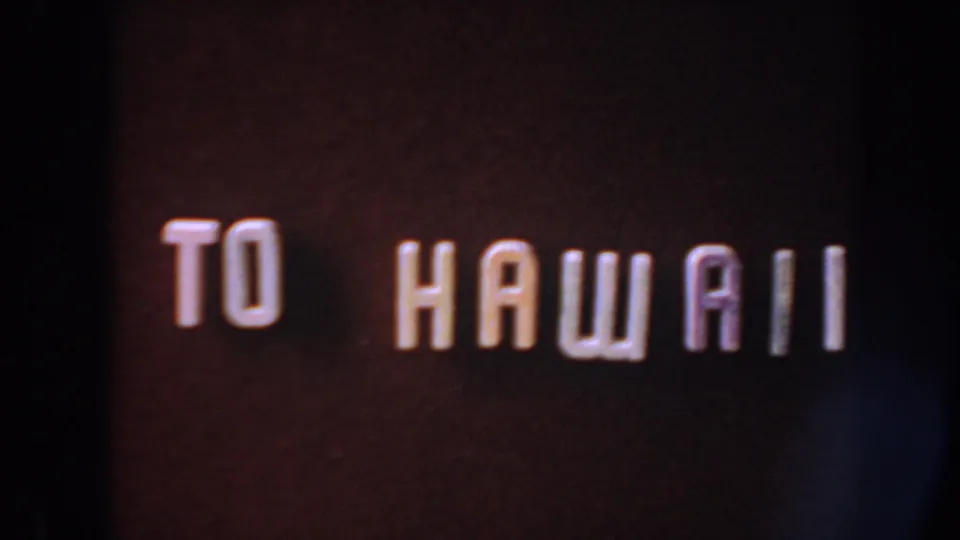8mm home-movie title card with white retro lettering reading 'TO HAWAII' against a dark reddish background.
