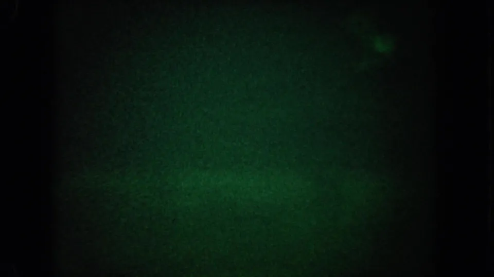 Low-light 1962 California 8mm underwater frame with grainy green water and barely visible marine movement at the right edge.