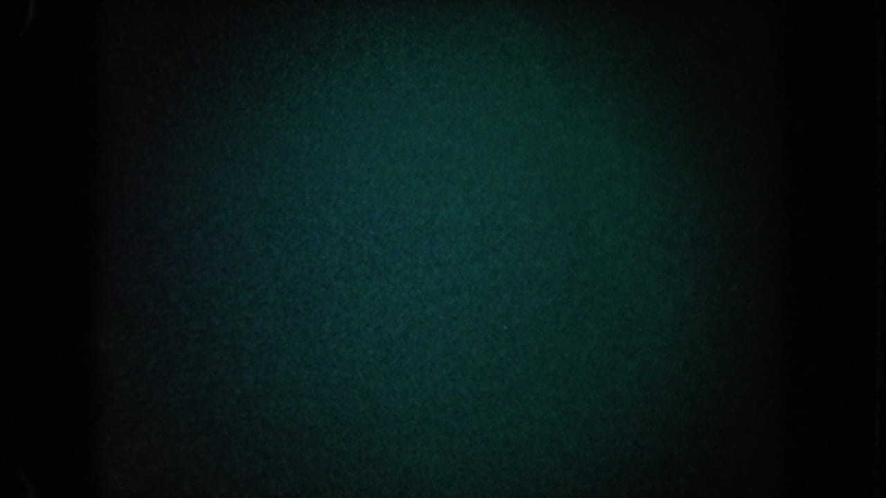 1962 California 8mm frame with heavy darkness, blue-green grain, a central black band, and very faint light variation.