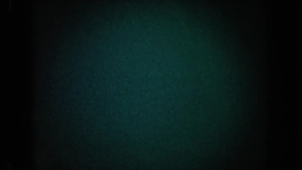 1962 California 8mm frame with heavy darkness, blue-green grain, a central black band, and very faint light variation.