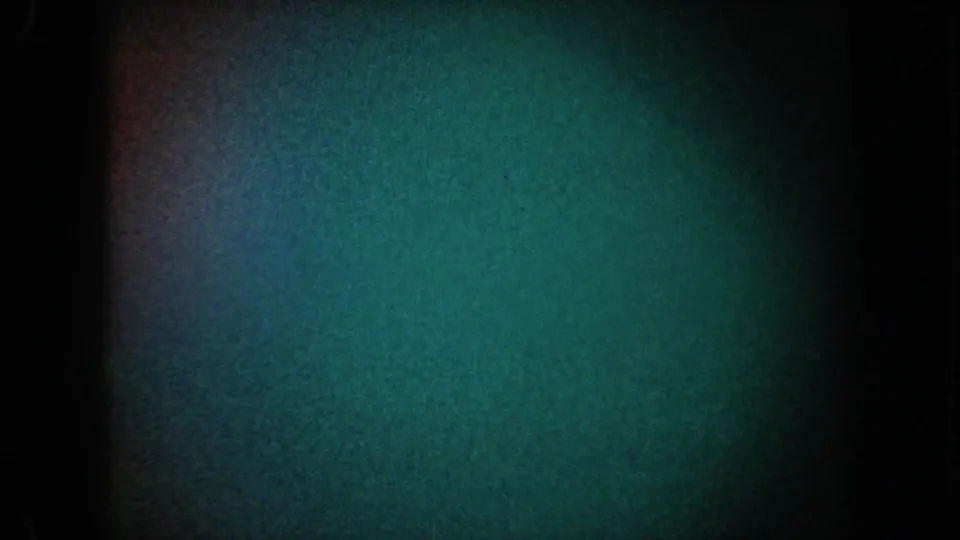 1962 California 8mm frame showing a dim green-blue underwater-like field, coarse grain, and dark gate edges with no identifiable subject.