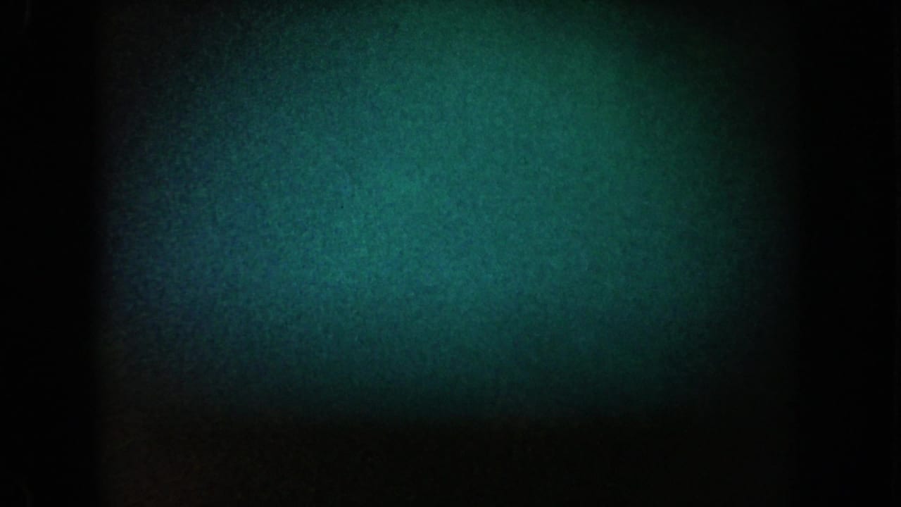 1962 California 8mm frame with green-blue low-light texture, a dark central band, and heavy grain obscuring any clear subject.