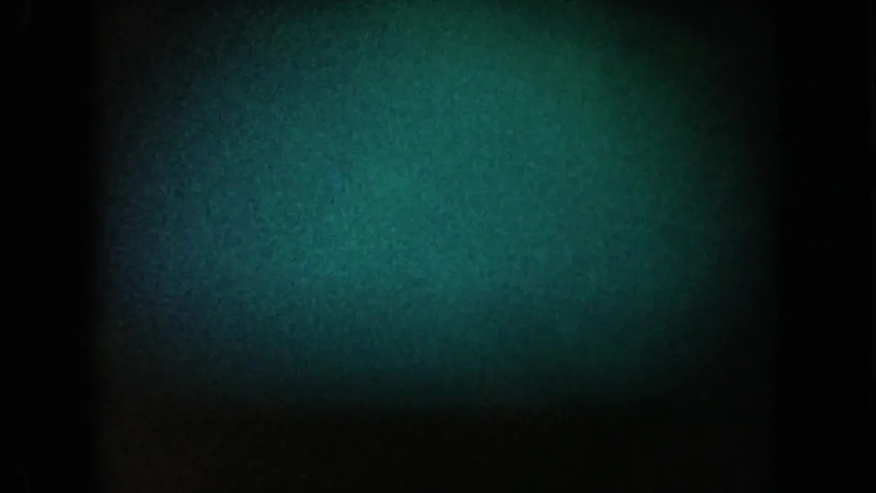 1962 California 8mm frame with green-blue low-light texture, a dark central band, and heavy grain obscuring any clear subject.