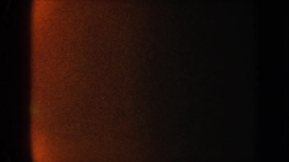1962 California 8mm frame with mostly dark exposure, orange film flare, and a faint aquarium viewing edge.
