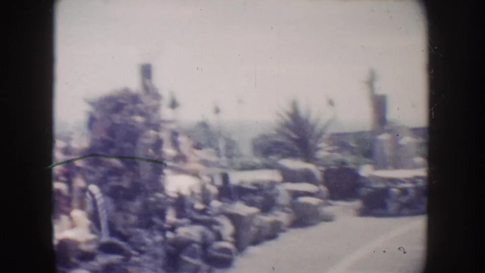 Soft 8mm view of a California coastal garden, with a rock sculpture or fountain, palm-like plants, stone edging, and the ocean horizon behind it.