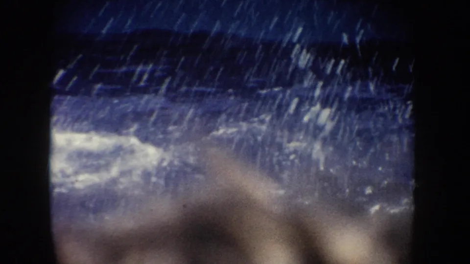 1962 California home-movie frame with spectators blurred behind a blue pool, partly obscured by spray and dark frame borders.