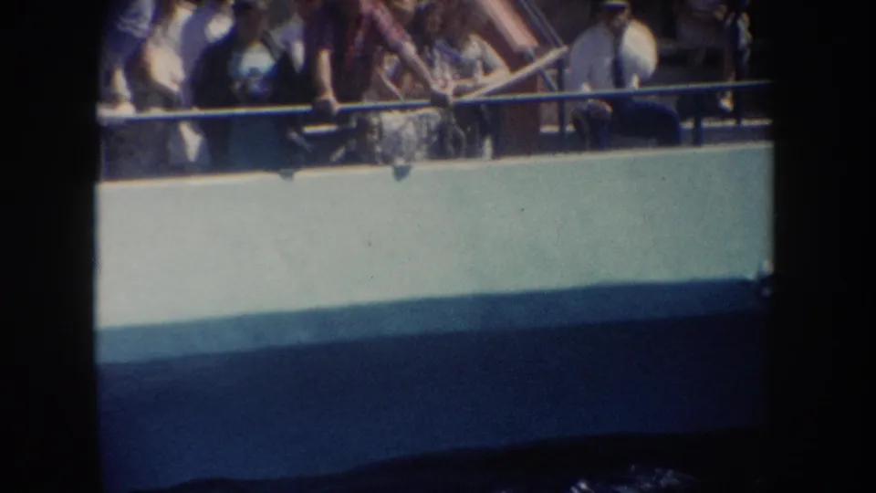 1962 California home-movie frame showing passengers gathered at a boat rail, looking down toward the water.