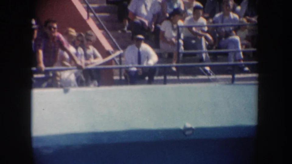 1962 California 8mm frame showing men and women on a boat deck watching the water from behind the railing.