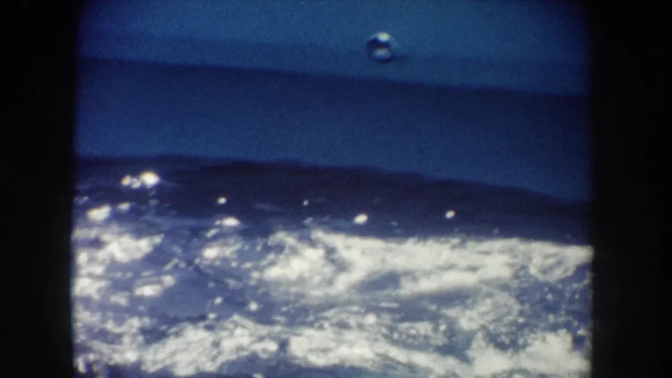 1962 California home-movie frame focused on turbulent pool water and foam after the dolphin movement.