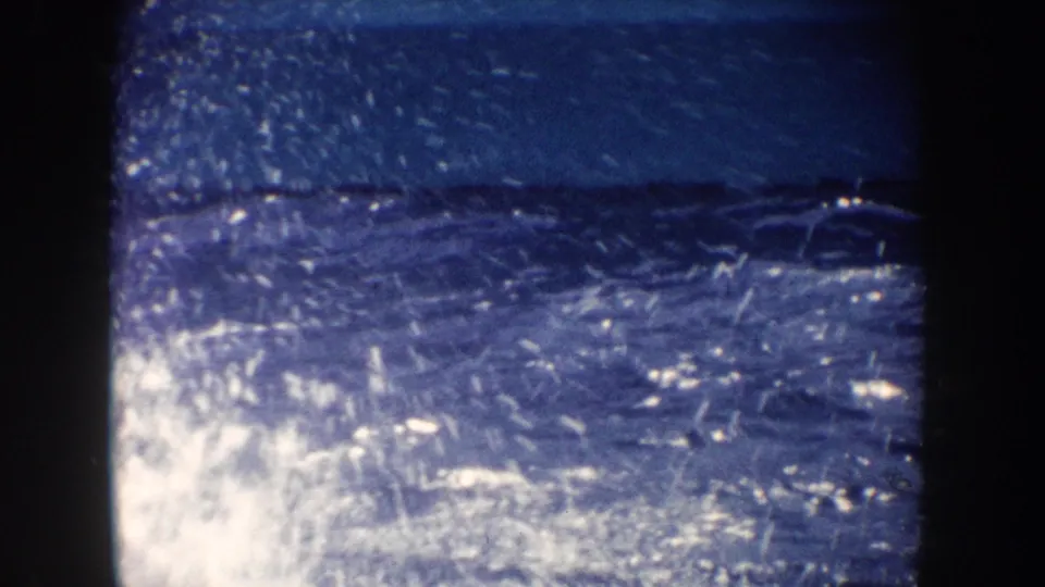 1962 California 8mm view of bright sun glare on blue water with spray and a distant dark surface shape.