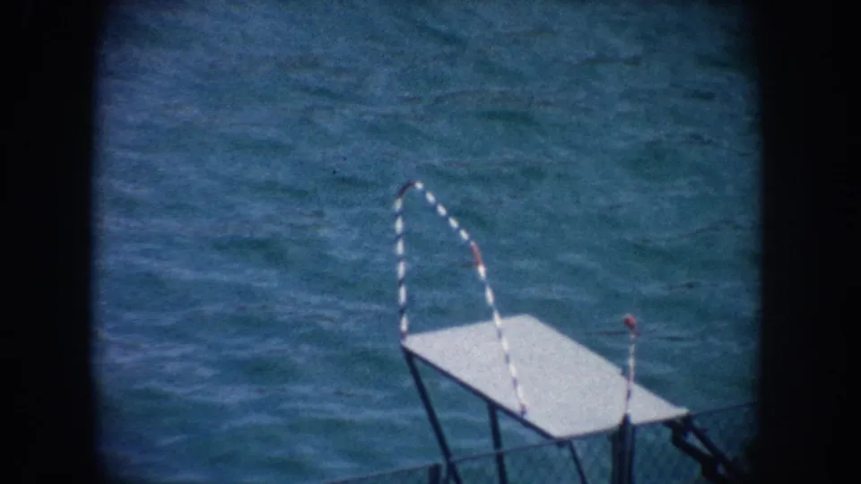 1962 California 8mm frame showing a white platform in the foreground and a yellow float near the far edge of a blue pool.