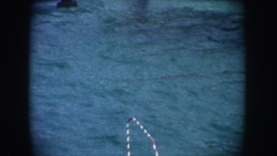 1962 California 8mm frame focusing on the striped performance pole and blue pool water after the seal has moved out of view.