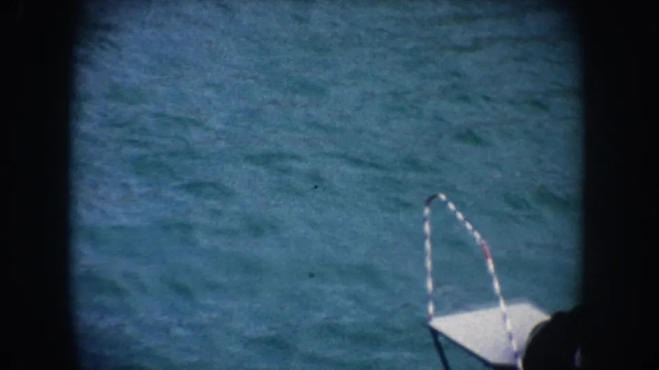 1962 California 8mm frame showing rippling blue pool water, a small platform or ladder edge, and heavy dark film borders.