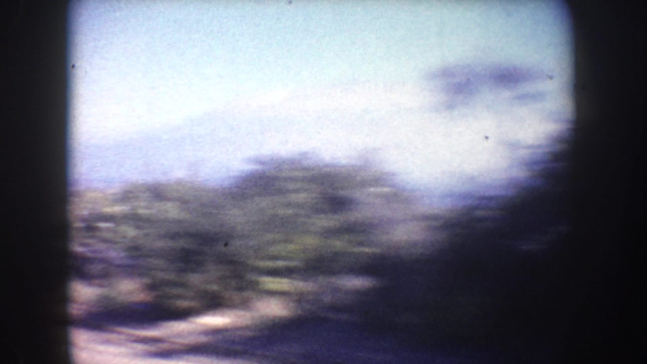 1962 California 8mm road-trip frame with motion-blurred roadside scenery seen from inside a vehicle.