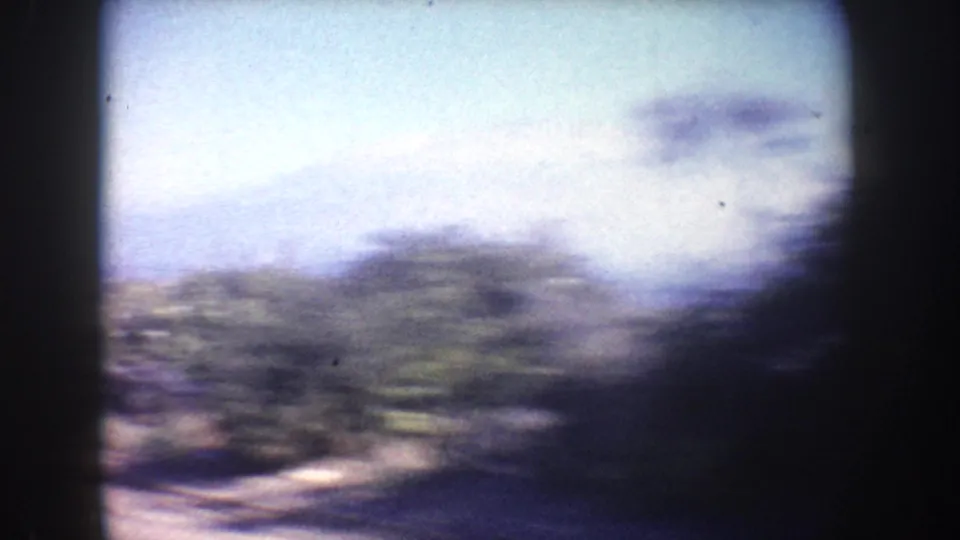 1962 California 8mm road-trip frame with motion-blurred roadside scenery seen from inside a vehicle.