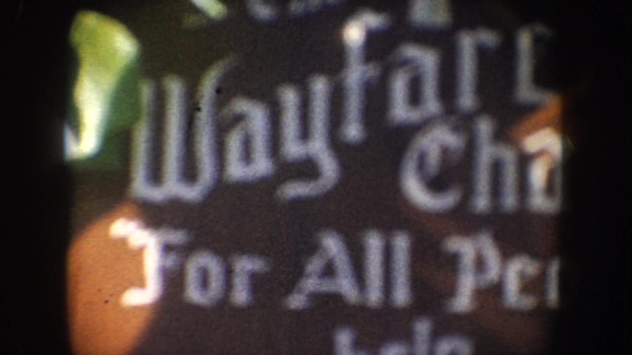 Close, blurred partial sign reading Wayfarer and For All Pe with dark frame edges.