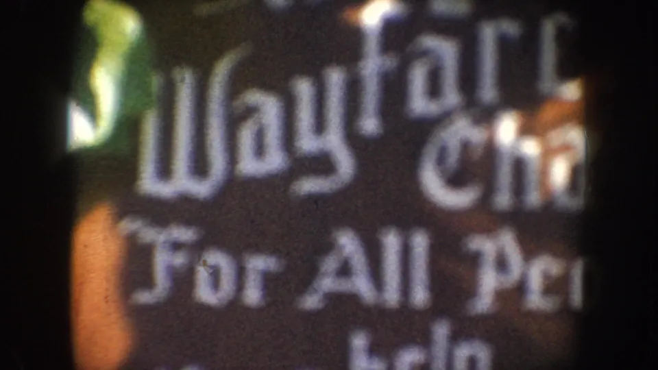 1962 California home-movie frame showing a blurred Wayfarer sign and partial For All People text.