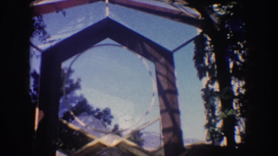 1962 California frame emphasizing the upper geometric arch, blue sky, trees, and the partially visible religious stonework below.