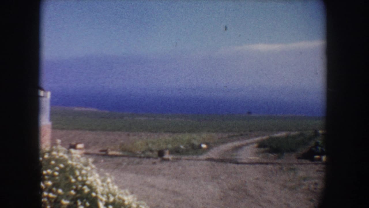 1962 California home-movie view of a dirt road, open fields, and blue sky from a rural roadside position.