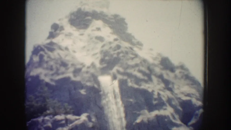 1962 Anaheim home-movie frame showing a waterfall on the rocky Matterhorn-style mountain facade.
