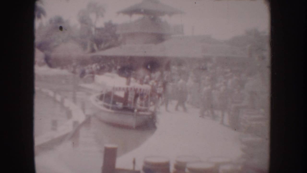 Small boat at the dock with visitors clustered on the walkway and water at left.