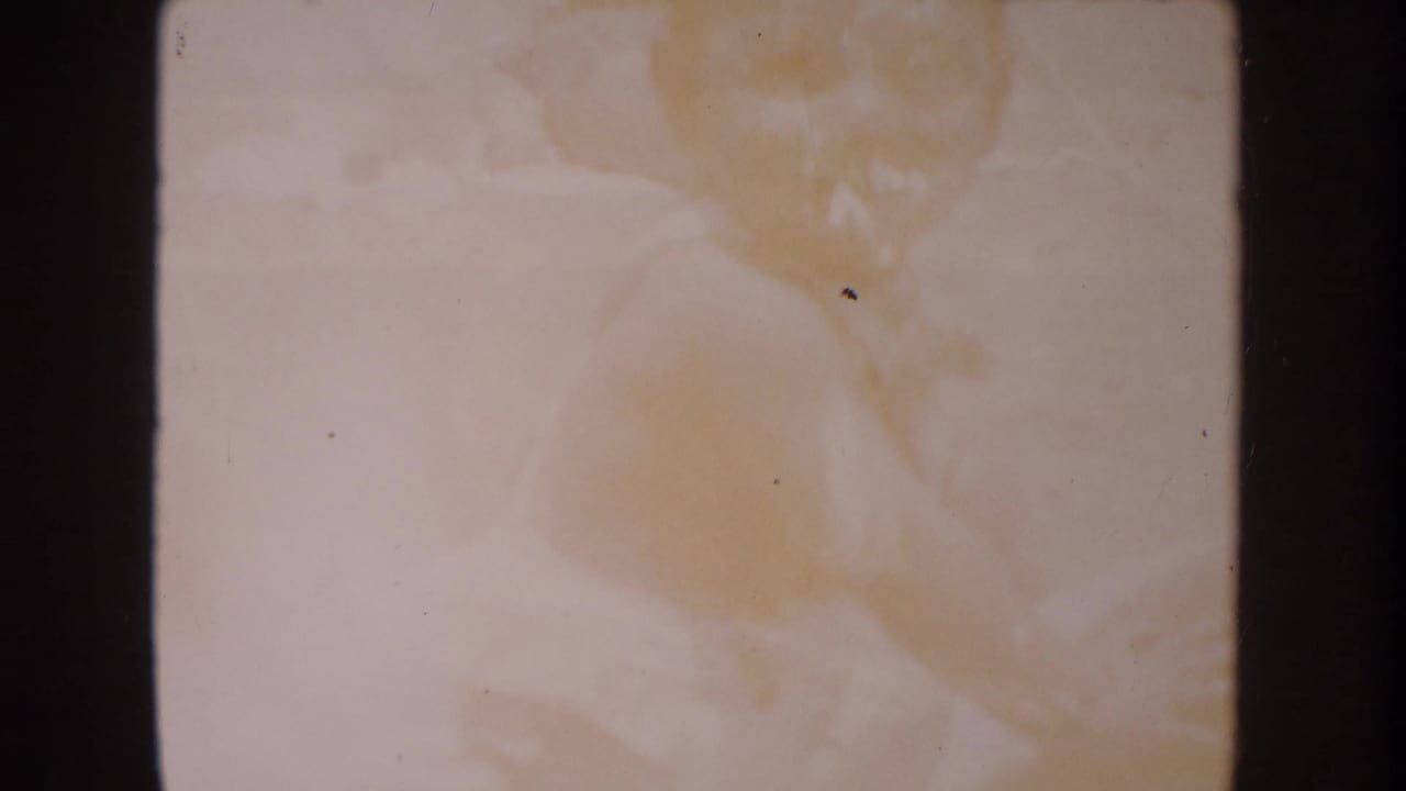 Anaheim 1962 8mm frame appears mostly blank, with warm discoloration, dust specks, scratches, and heavy dark borders.