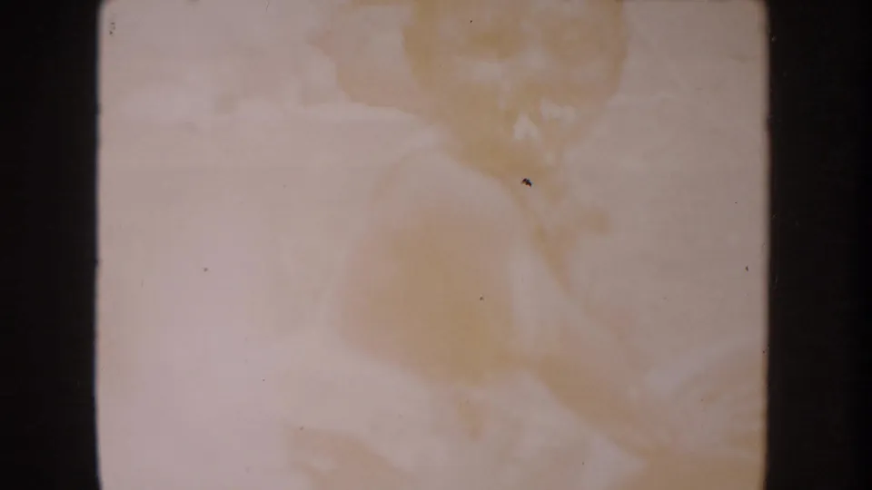Anaheim 1962 8mm frame appears mostly blank, with warm discoloration, dust specks, scratches, and heavy dark borders.