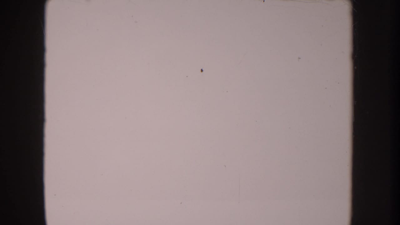 Anaheim 1962 8mm frame is nearly blank, showing pale faded emulsion, small dust marks, and dark vertical film borders.