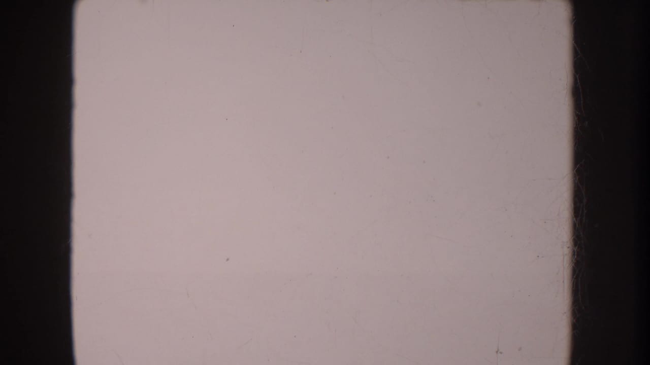 Faded 8mm frame from the 1962 Anaheim clip, showing a mostly pale overexposed area with dark film borders and dust marks.