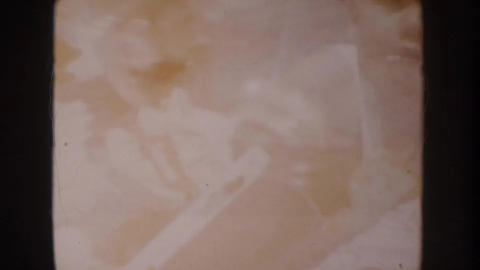 Faded 1962 Anaheim 8mm frame with heavily blurred pale forms, dust, scratches, and dark borders from the film gate.