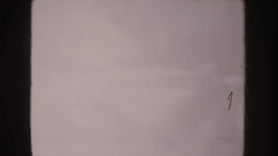 Mostly blank faded 8mm frame from the Anaheim home movie, showing overexposure, gate edges, dust, and a small surface mark.
