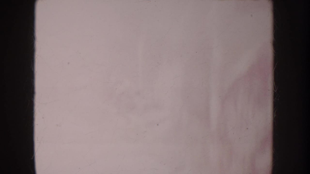 Very soft faded frame with pale surface, dark film edges, and indistinct toy shapes.