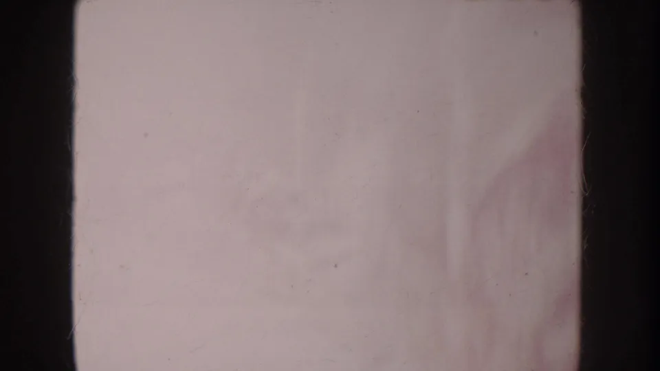 Soft, faded 1962 Anaheim 8mm frame with dark gate edges and indistinct toy-play shapes on a pale surface.