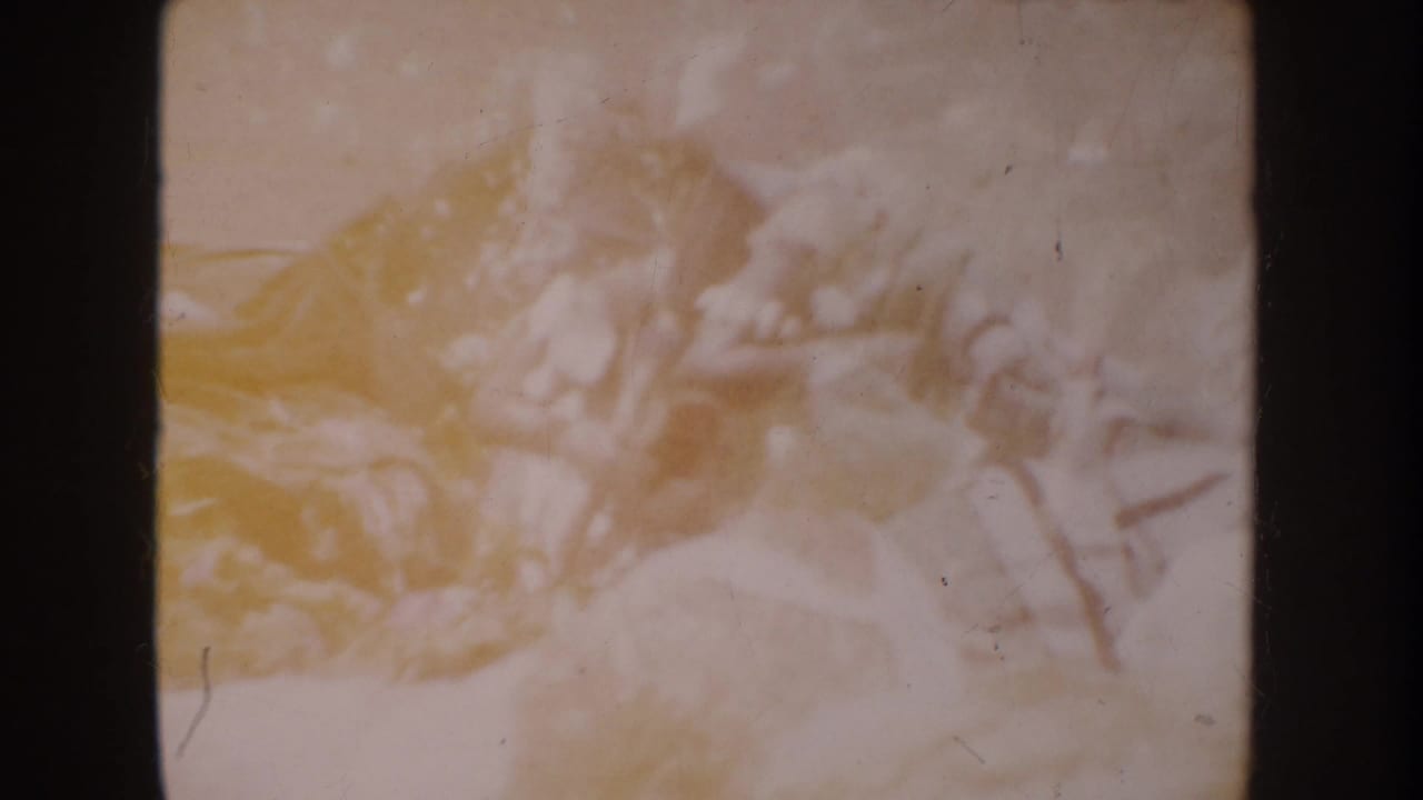 Faded 1962 Anaheim 8mm frame showing small toy soldiers or figures clustered on a pale surface.