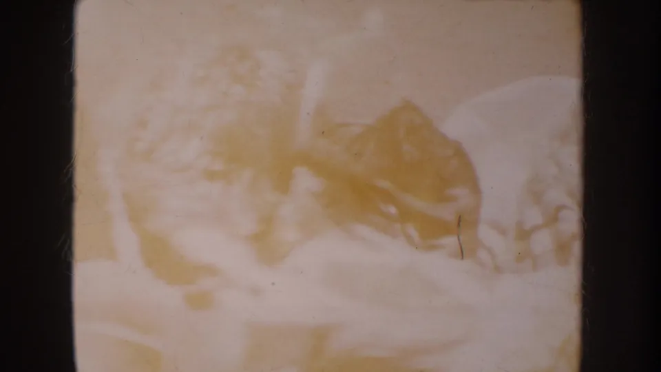 Faded 1962 Anaheim 8mm frame showing a toy soldier or small figure on a pale surface with visible film wear.