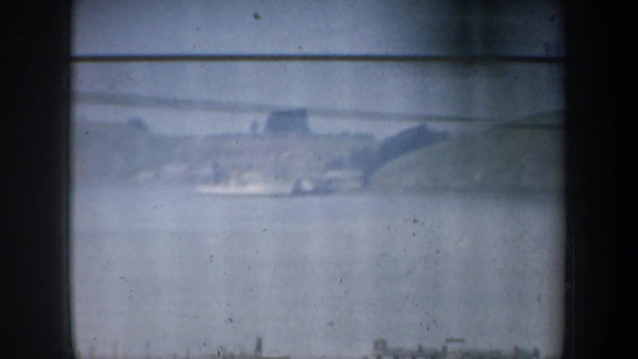 Soft distant view across water with hills and shoreline structures.