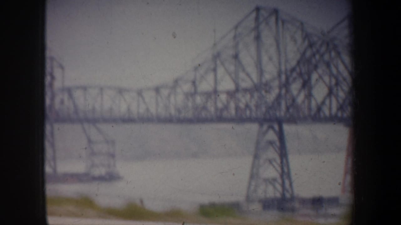 1957 San Francisco-area 8mm frame showing a large steel truss bridge over water, soft and slightly faded.