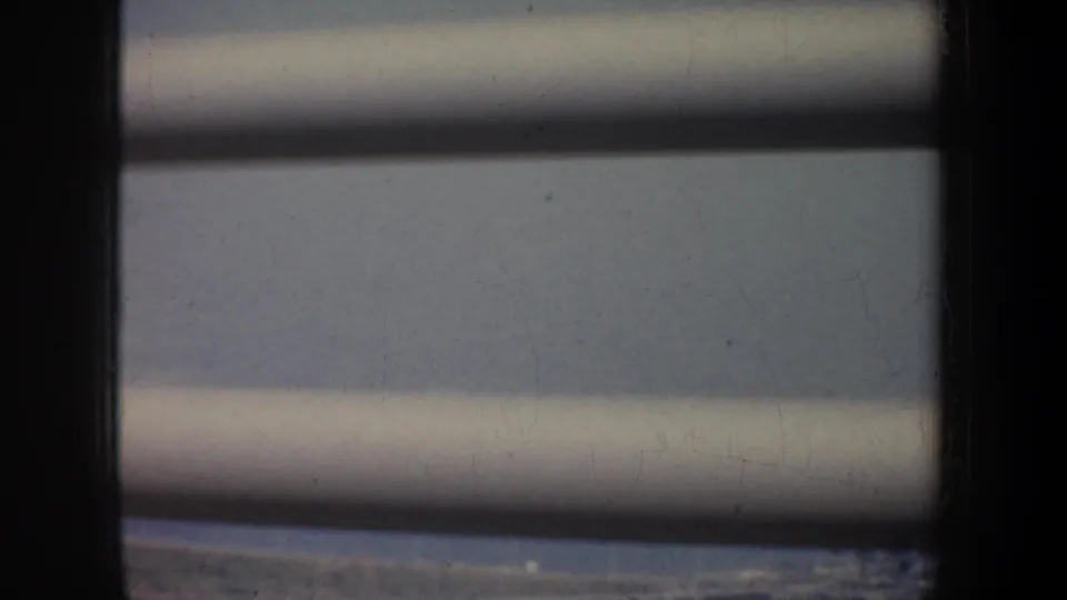 Obscured San Francisco travel view through blinds and dark window framing, softened by 8mm film grain.