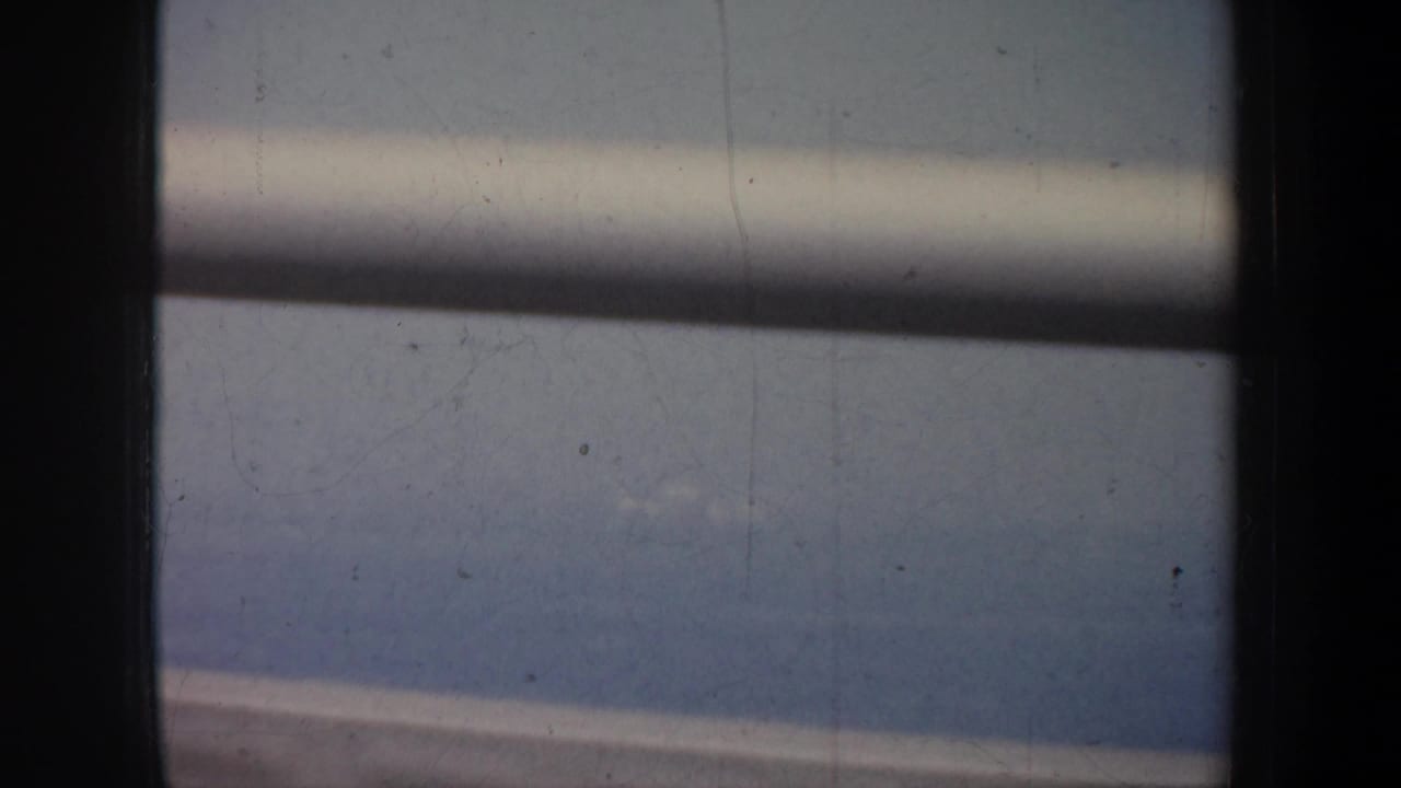 Dark bridge supports divide a soft view of water, sky, and distant land.