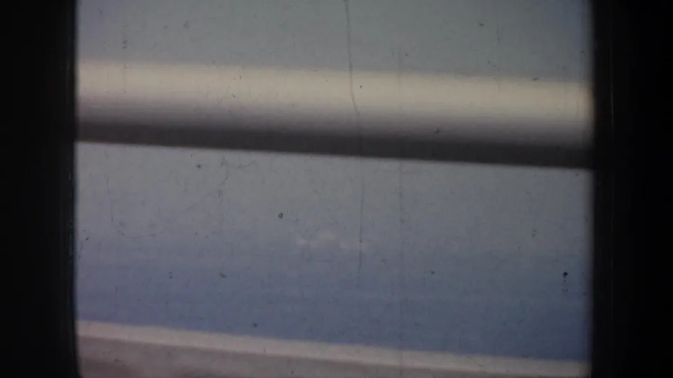 Bridge structure blocks part of a 1957 San Francisco bay view, with water and distant shoreline visible beyond.