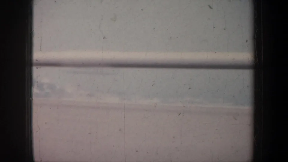 Soft 8mm frame from a San Francisco bridge crossing, showing railing, blue water, and hazy land in the distance.