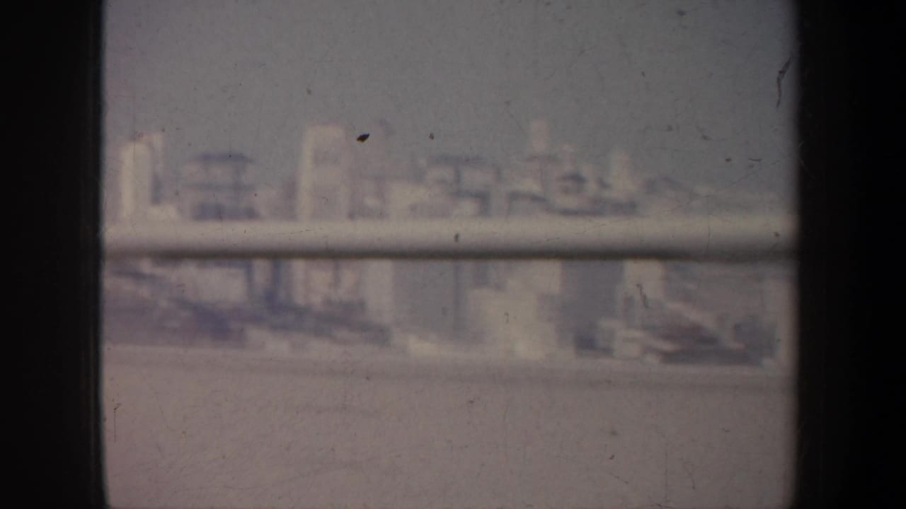 Soft, hazy city skyline seen through a dark window frame and horizontal rail.