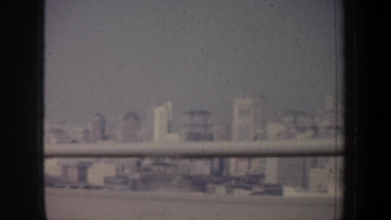 Blurred waterfront city buildings framed by window bars and dark vertical dividers.