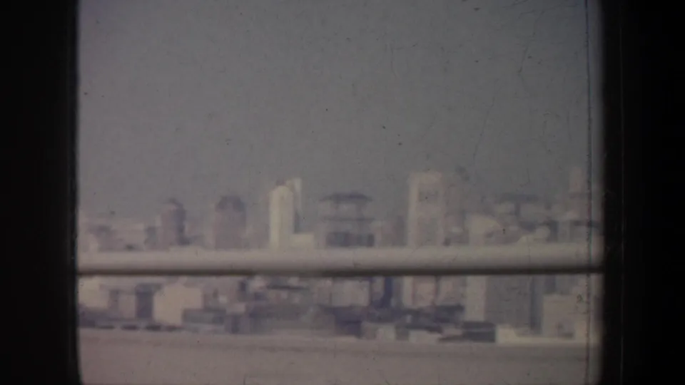 A soft 1957 San Francisco urban view shows waterfront buildings through window rails and dark dividers.