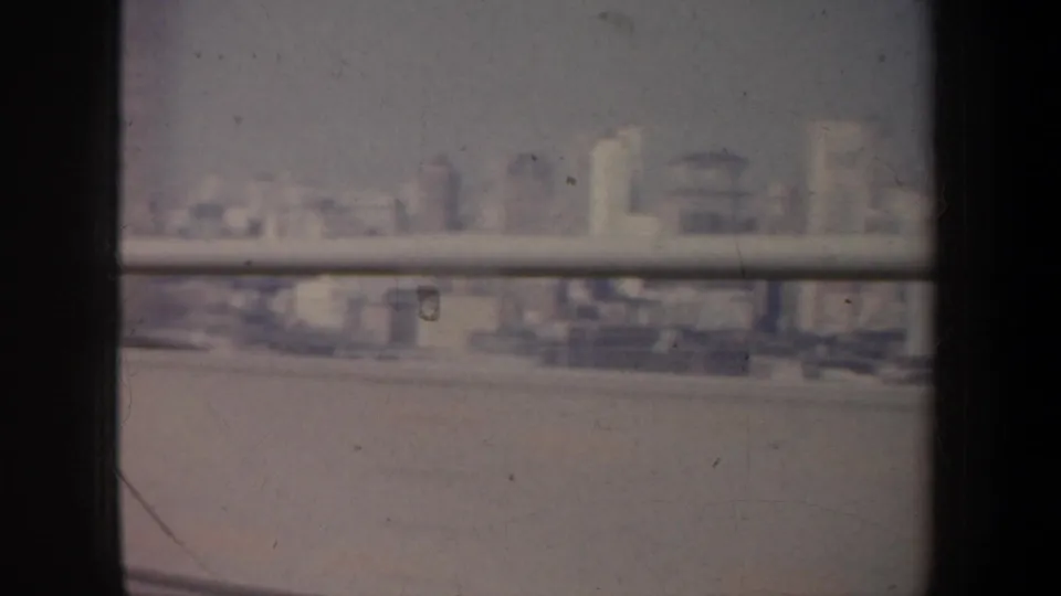 The home-movie view continues across hazy San Francisco buildings, partly obscured by window framing and film wear.